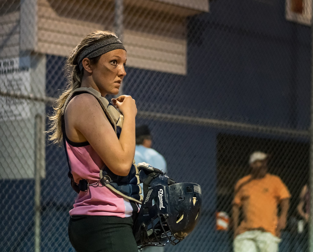 A softball catcher has a quiet moment in between pitches