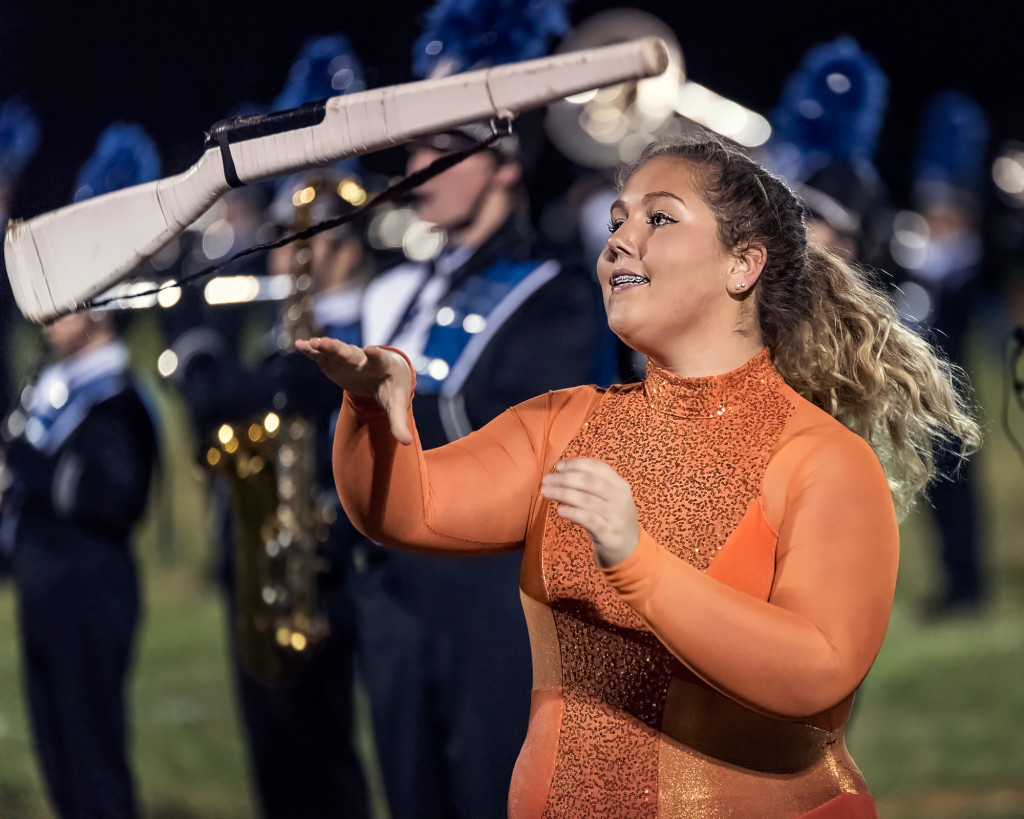 A Color Guard Member tossing a rifle during a marching band performance